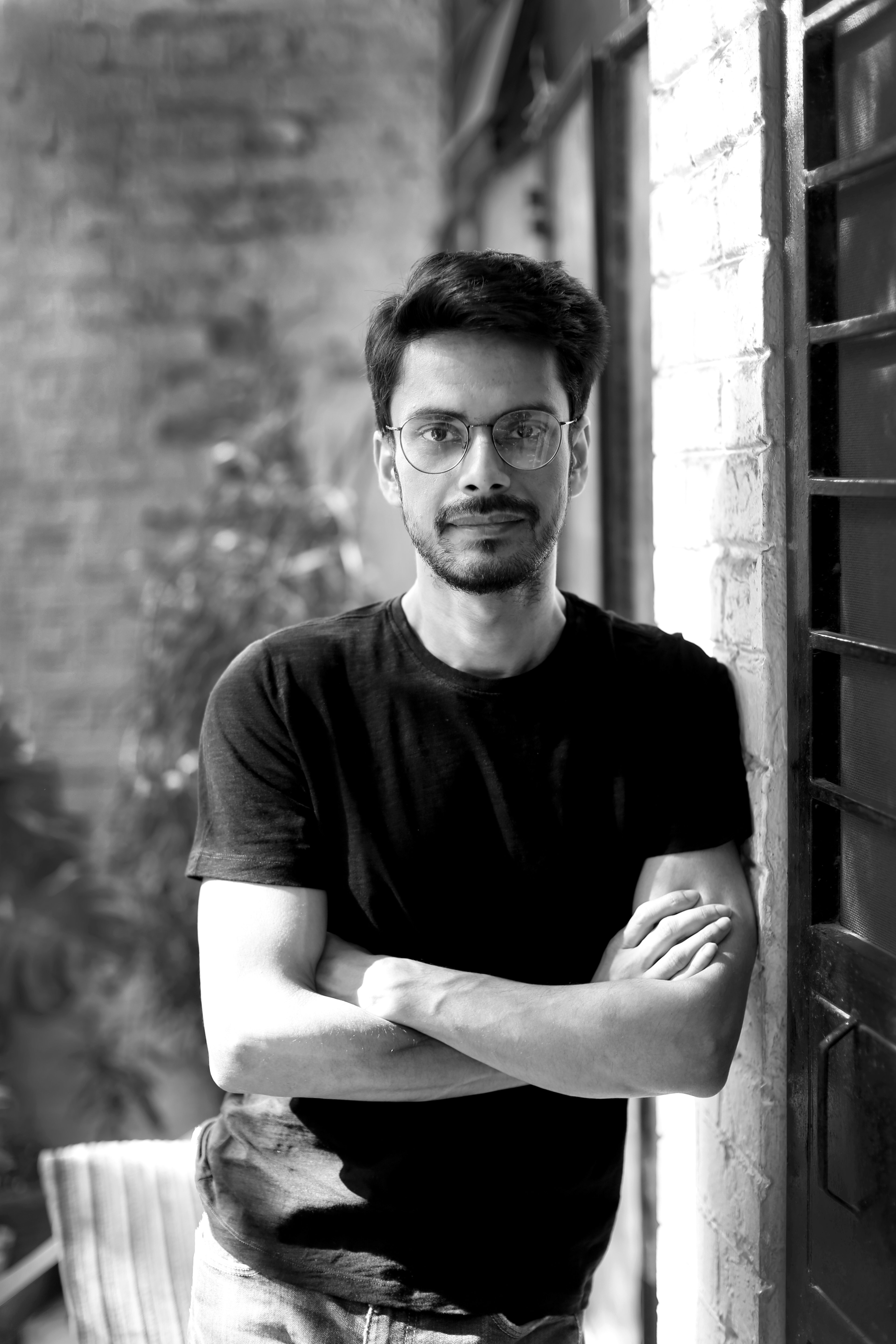 A black-and-white headshot of Shaunak Sen, an Indian man with glasses and a beard and wearing a black t-shirt. He is director of ‘All That Breathes.’  Courtesy of Cinetic Media.
