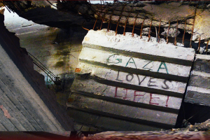 A concrete slab inside a collapsed building with "Gaza Loves Life!" painted on it