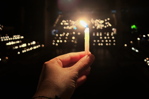 a hand hold a camera in front of far away lights. 