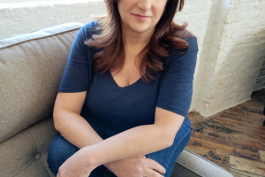 Headshot of Tia Lessin. A woman with white skin, brown eyes, and brown hair smiles at the camera.