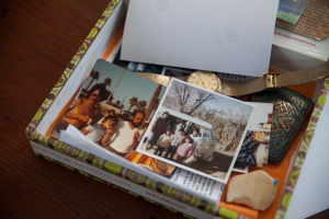Cigar Box with family photos, a gold watch, turquoise inlaid belt buckle, white buffalo carving.