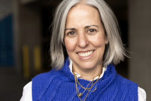 Headshot of Jennifer Sofio Hall. Fair skinned woman with a blue sweater and white shirt. Shoulder length hair and a wide smile.