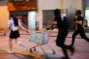 A still from 'Do Not Split', nominated for Best Documentary Short at the 93rd Academy Awards. The frame shows three young protestors in Hong Kong running down an empty street with a shopping cart.
