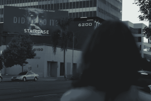 Margaret Ratliff is a white woman. Her back faces the camera as she looks at a billboard advertising the TV series ‘The Staircase.’ From Jennifer Tiexiera and Camilla Hall’s ‘Subject.’ Photo courtesy of Susan Norget Film Promotion.  