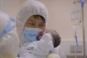 An Asian man, wearing a protective hood and mask, holds his newborn baby. From Yung Chang's 'Wuhan Wuhan."  Courtesy of Stars Collective Films Entertainment Group, Inc.