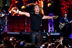 Filipino-American musician Arnel Pineda performing in a concert. He is wearing a black shirt and leather pants. Image from Ramona Diaz’s ‘Don't Stop Believin': Everyman's Journey.’ Courtesy of Amazon Prime.