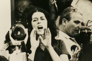 Activist Lois Gibbs is a white woman with short dark hair seen shouting to a crowd in an archival image. From Mark Kitchell’s 2012 film 'A Fierce Green Fire'. Courtesy of Mark Kitchell