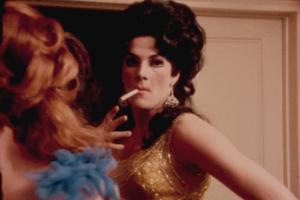 A drag performer in a golden dress, wearing a wig, smoking a cigarette. From Frank Simon's 'The Queen' Courtesy of Kino Lorber.