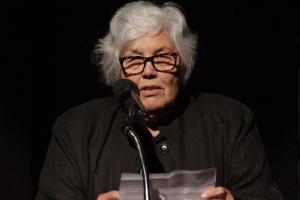 Lourdes Portillo, a Latinx woman with white hair, glasses and a black top, accepting the IDA Career Achievement Award in 2017; Portillo is the only filmmaker to have earned IDA Documentary Award in four different decades. Photo: Susan Yin