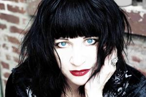 Lydia Lunch, a white woman with black hair cut in bangs. She is wearing bright blue contact lenses and red lipstick. From Beth B’s ‘Lydia Lunch: The War is Never Over’. Courtesy of Kino Lorber.