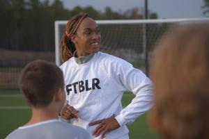 Soccer player Jessica McDonald is a Black woman in her 30s. Here, she is wearing a white shirt that says “FTBLR” and her hair is tied back. Image from Andrea Nix Fine and Sean Fine’s ‘LFG.’ Courtesy of HBO Max 