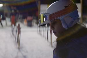 Sarah Rose Huckman, a young transgender woman in skiing gear. Ski resort behind her. She is the protagonist of ‘Changing the Game’ (Directed by Michael Barnett)
