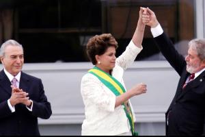 Dilma Rousseff, the former president of Brazil, is applauded  while  Luiz Inácio Lula da Silva, her predecessor, who was just elected president for the second time, on October 30, 2022, raises her hand in the air. From Petra Costa’s ‘The Edge of Democracy.’ Photo courtesy of Netflix. 
