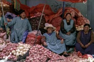 Women sit and laugh among a heap of onions in a marketplace. From Kiro Russo’s ‘El Gran Movimiento.’ Courtesy of Cinema Tropical.
