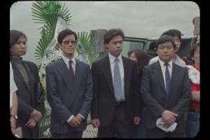 Four Chinese dissidents--one woman and three men--dressed in suits, stand in New York City's Battery Park. From 1989 footage from the suspended project 'Tiananmen/China Today.' Courtesy of Christine Choy 