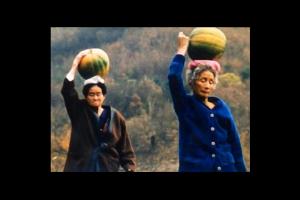 Two older women walk while balancing squash on their head, from 'Habitual Sadness.'