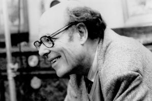 An older man wearing glasses laughs. 