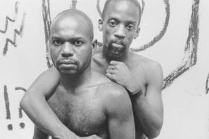 Two Black men embrace each other. Marlon Riggs' 'Tongues United' is looked at as an exploration of regional exile in tandem with personal exile in 'Between the Sheets, in the Streets Queer, Lesbian, Gay Documentary'.