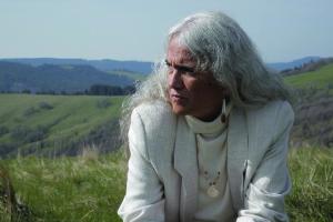 An elder Yurok woman in front of green landscape