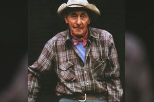 A man wearing a flannel and cowboy hat from 'Woodsmen and River Drivers.'