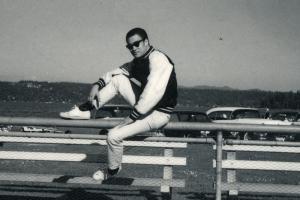 A man is sitting on a ledge in parking lot