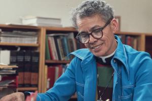 A older Black person with gray hair wearing a blue coat.
