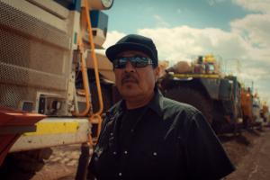 Indigenous coal miner poses for photo in front of plant equiptment