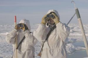 Young hunters in Alaska scan an icy horizon with binoculars. 