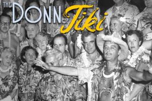 A black and white photo of a large group of middle-aged and older partygoers with "tiki" style clothing, a man in the center holds out his arms wide.