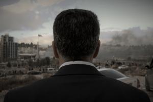 Main subject of film looks away from camera towards his town in a suit.