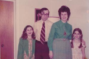 A late-20th century family photo with Mom and Dad in the middle and two daughters on either side. 