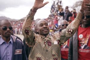 An Zimbabwe man raising his hands at crowds cheering him