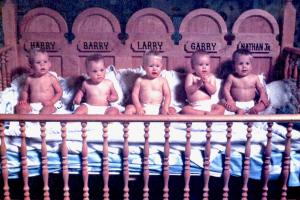 Old photo of the quintuplets sitting in their cribs.