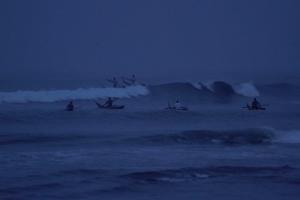 A group of Peruvian fishermen going into the ocean at dawn.
