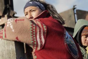 A Native American woman leaned over a fence