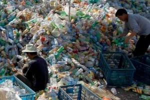 Two people searching through piles of plastic bottle