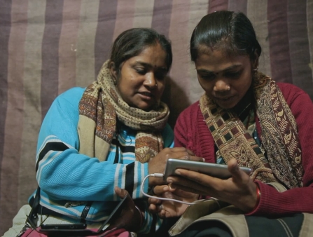 Two women look at a phone.