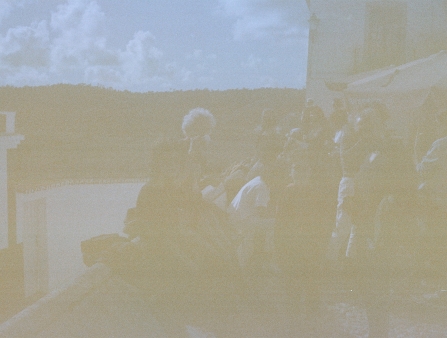 A group of people gather on a balcony, on expired film.