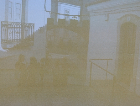 Damaged photograph of a group of people walking down a narrow street.
