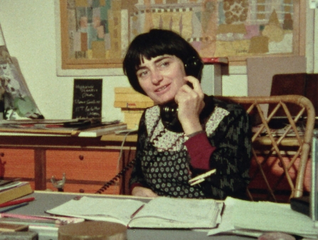 A woman with a dark bob talks on the telephone in a office.