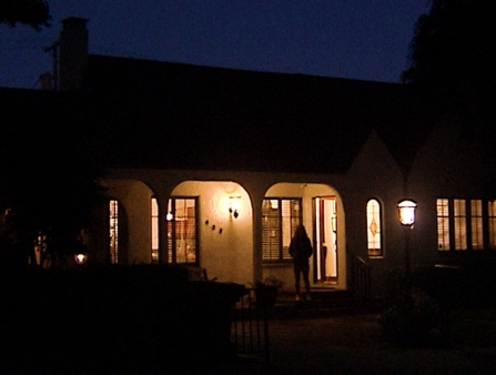 A digital video still of a man at the door of a house.