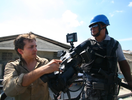 A man films an UN worker in a blue helmet.