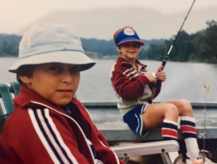 Two young boys wearing red, blue, and white striped jackets on a fishing boat.