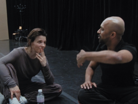 A man and a woman are sitting on the floor in a rehearsal space