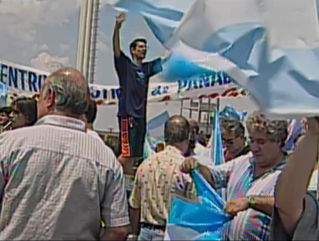 Grainy pixelated image of a group of people at an outdoor protest flying the Argentinean flag