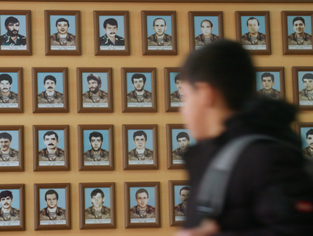 A blurry boy passes by a memorial wall.