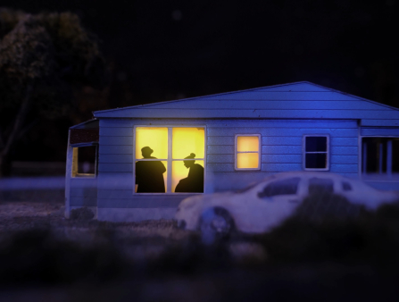Shot of a miniature house at night with a car out front.