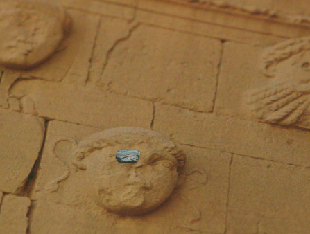 Stone carving of a medusa figure is covered where it's eye should be with a cut out photograph of an eye