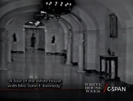 Black and white C-SPAN screenshot titled Tour of the White House with Mrs. John F. Kennedy where you can see the figure of a woman long ways away in an ornate hallway