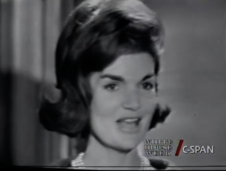 Black and white blurry C-SPAN screenshot of a white woman with a fashionable bob hairdo wearing pearls mid-sentence